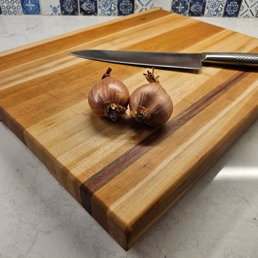 Extra large cherry edge grain cutting board with walnut and purple heart stripes.